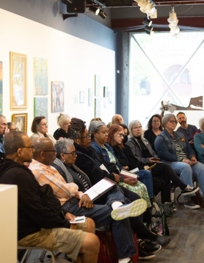 Group of people sitting in lines in gallery space for education talk.