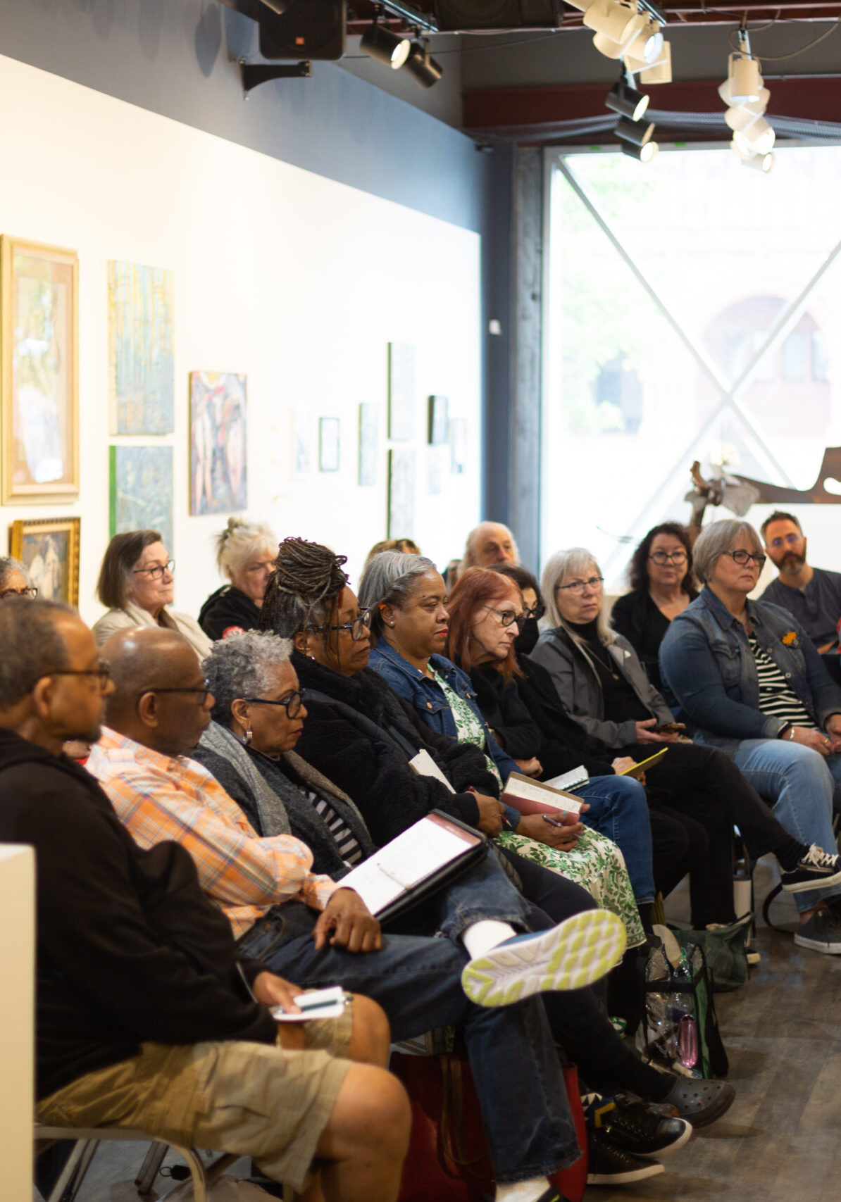 Group of people sitting in lines in gallery space for education talk.
